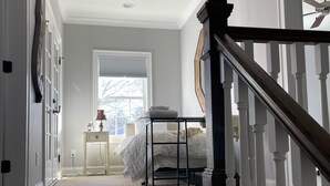 Un dormitorio con cama, mesita de noche y ventana.