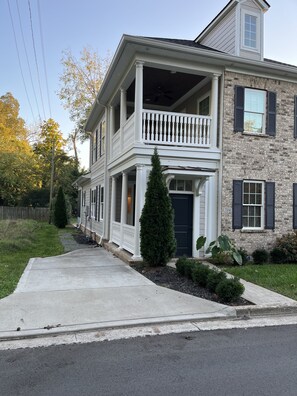 Une maison à deux étages dotée d’un balcon, d’un porche et d’une façade en pierre.