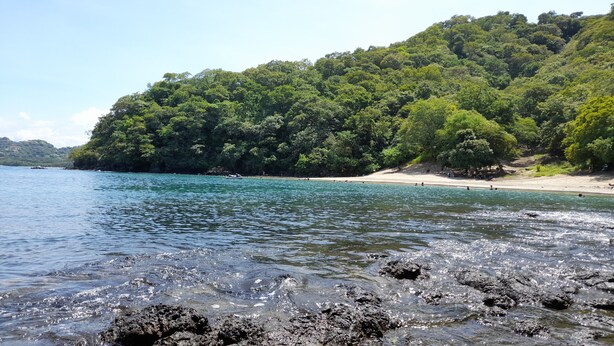 A beach with clear water, rocky foreground, and a forested hillside. - Villa in a Quiet and Safe Residential Area for 6 people. (Comunidad, Carrillo)