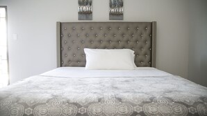 A neatly made bed with a patterned bedspread and a tufted headboard. - Ocean View Terrace (Montego Bay)