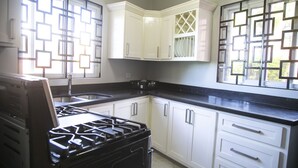 A kitchen with white cabinets, a black countertop, and a gas stove. - Ocean View Terrace (Montego Bay)