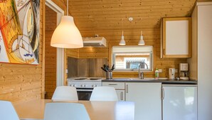 Eine moderne Küche mit weißen Geräten, ein Essbereich mit weißen Stühlen und Pendelleuchten.