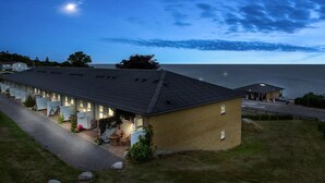 A coastal hotel with multiple rooms, a parking area, and a view of the sea.
