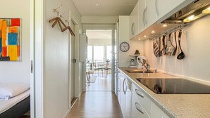 A modern kitchen with white cabinets, a stainless steel sink, and a clock on the wall.
