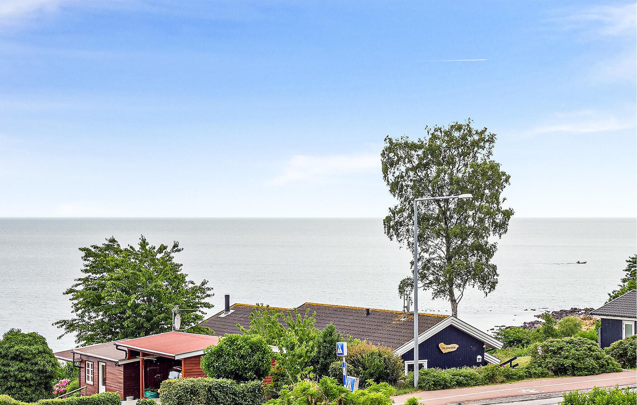 A coastal residential area with houses, a street lamp, and a view of the sea.