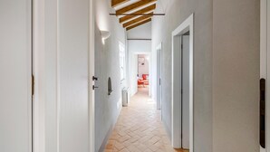 Un pasillo estrecho con paredes blancas, vigas de madera en el techo y un piso con motivo de espiga.