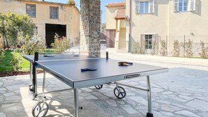 Una mesa de ping pong en un patio exterior con suelo y pilar de piedra.