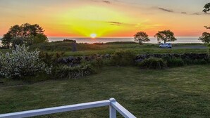 A sunset view from a grassy area with a stone wall and a white fence. - Gorgeous home in Svaneke with WiFi (Svaneke)