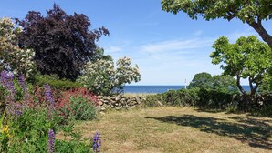 A garden with various plants and a stone wall leading to a view of the sea. - Gorgeous home in Svaneke with WiFi (Svaneke)
