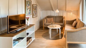 Un salon confortable avec un téléviseur à écran plat, un canapé, une table basse ronde et une bibliothèque.