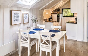 A dining area with a white table and chairs, framed artwork, and a hanging light fixture.