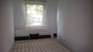 Une chambre à coucher avec un lit, une table de chevet, une lampe et une fenêtre avec des rideaux.