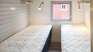 Ett litet, smalt rum med två sängar, ett fönster och två vägglampor.