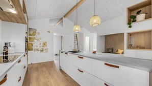 Une cuisine moderne avec des meubles blancs, des éléments décoratifs en bois et des luminaires suspendus.