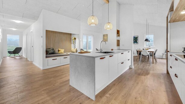 Une cuisine moderne dotée d’un îlot central, de planchers en bois et de luminaires suspendus.