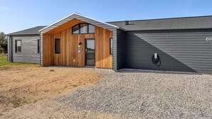 Un bâtiment moderne avec une entrée en bois, une allée gravillonnée et le numéro « 69 » affiché sur le côté.