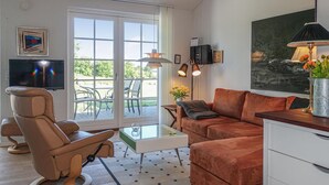 A modern living room with a leather sofa, a reclining chair, a glass coffee table, and a TV mounted on the wall. - Nice apartment in Allinge with WiFi (Allinge)