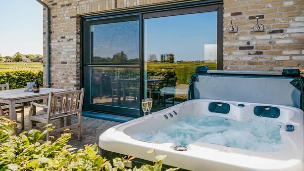 A spa area with a hot tub, wooden deck, and a glass door leading to a garden. - Awesome home in Diksmuide with WiFi (Diksmuide)