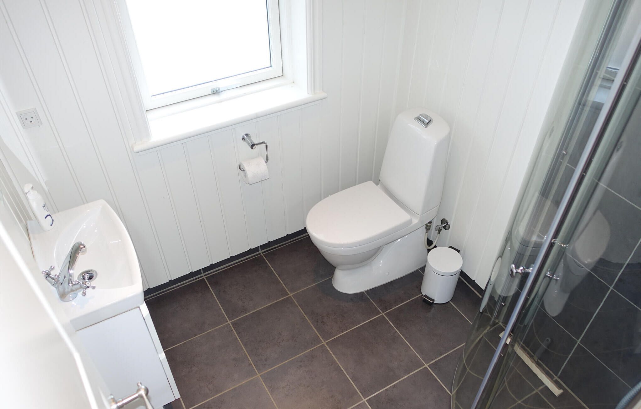 A bathroom with a white toilet, a sink, and a glass shower enclosure.