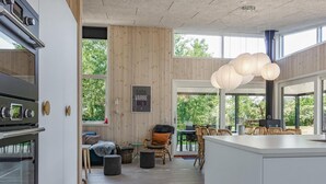 Una cocina moderna con horno empotrado y comedor con sillas de mimbre y un ventanal grande.