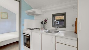 Eine moderne Küche mit weißen Schränken, einem eingebauten Ofen, einer Edelstahlspüle und einem Fenster mit Blick ins Freie.