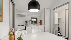 Eine moderne Küche mit weißen Schränken, einem Herd und einem Spülbecken. Über dem Spülbecken befindet sich ein Fenster, und auf der Arbeitsfläche steht eine Vase mit Blumen.