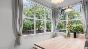 A room with a large window, a wooden table, and a vase with flowers. - Nice home in Nexø with kitchen (Nexø)