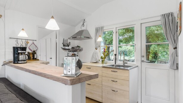 A modern kitchen with a central island, a sink, and a window with curtains. - Nice home in Nexø with kitchen (Nexø)