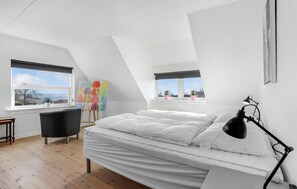 Ein Schlafzimmer mit einem Bett, einem Schreibtisch, einem Stuhl und einem Gemälde.