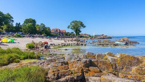 En strand med tält, en klippig kust och en klarblå himmel.