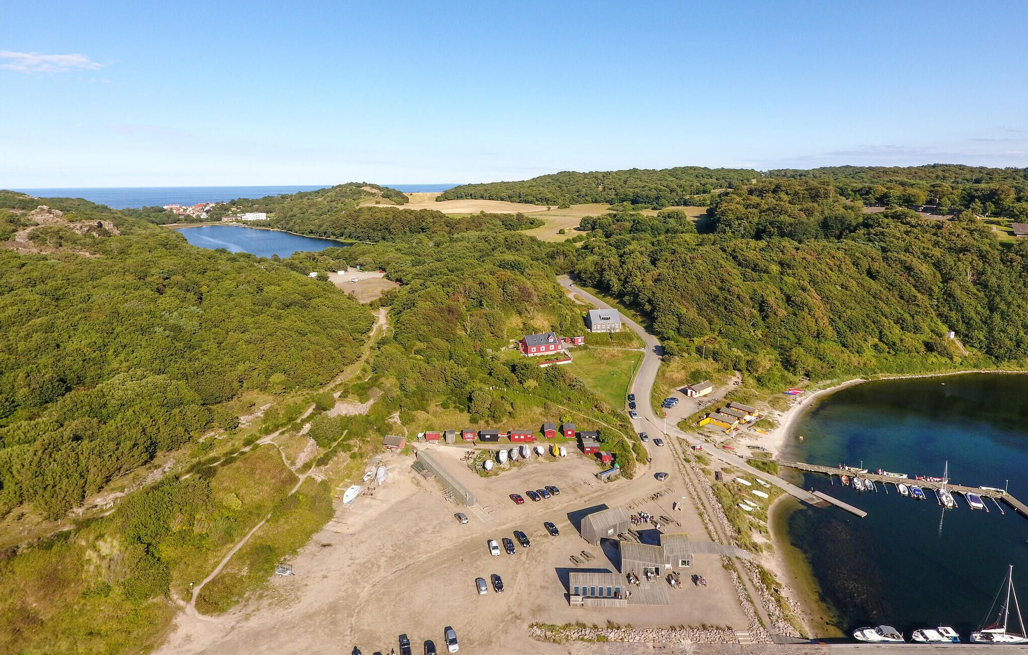 An aerial view of a coastal area with a marina, a parking lot, and a small cluster of buildings.