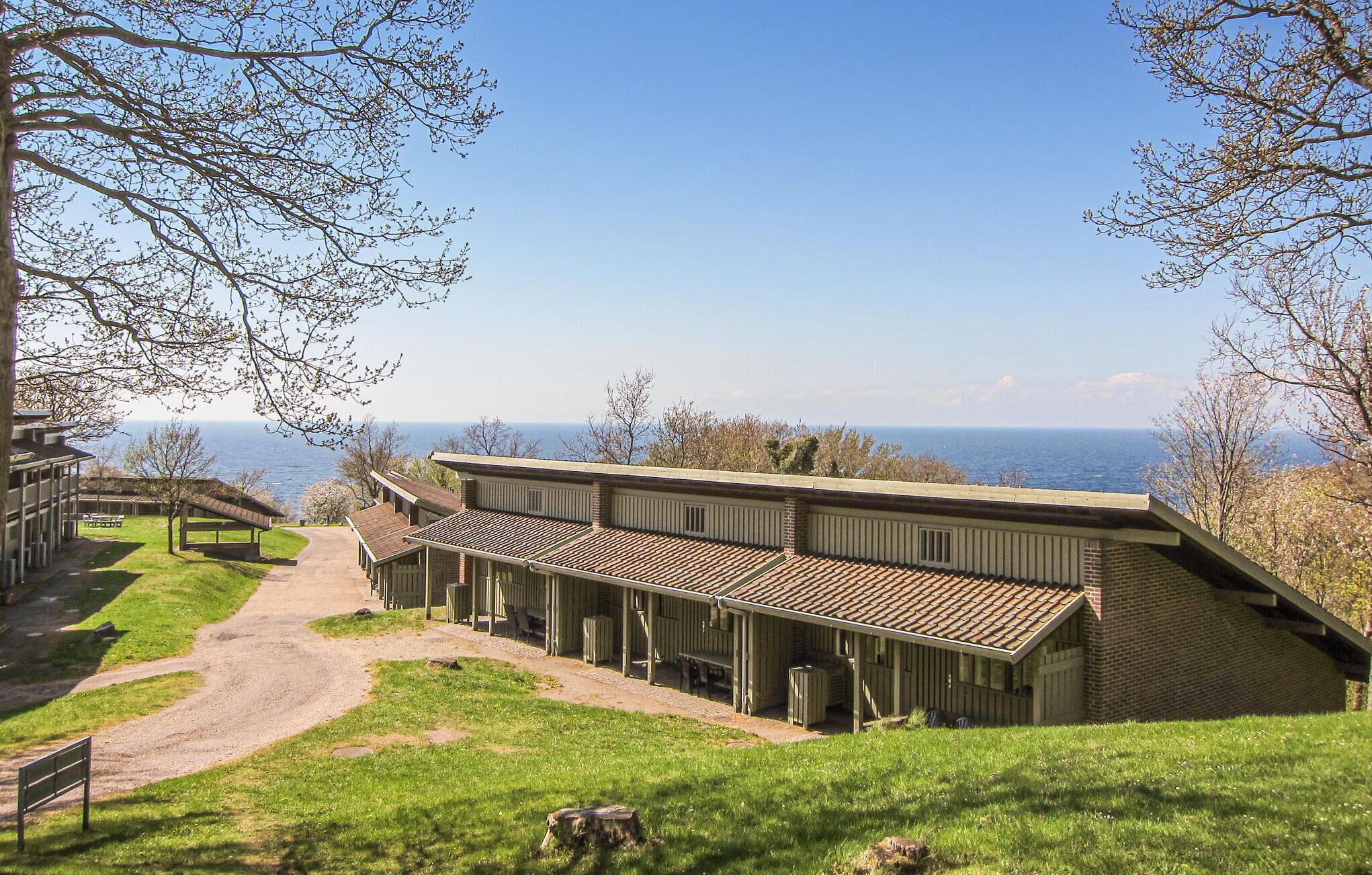 Un bâtiment doté d’une longue terrasse couverte, d’un chemin de terre menant à celle-ci et offrant une vue sur la mer.