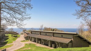 Un edificio con un'ampia veranda coperta, un sentiero sterrato che vi conduce e vista sul mare.