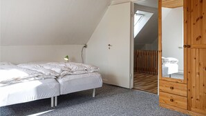 Un dormitori amb un llit, un armari de fusta i una porta que dona a una altra habitació.