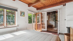A bedroom with a large bed, a wooden ceiling, and a view of a garden through the window. - Nice home in Nexø with WiFi (Nexø)