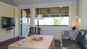 Una sala de estar con televisor, una mesa con bandeja, sofá y ventana con cortinas.