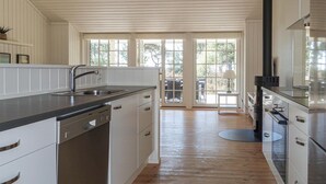 A kitchen with white cabinets, stainless steel appliances, and a large window. - 3 bedroom gorgeous home in Nexø (Nexø)