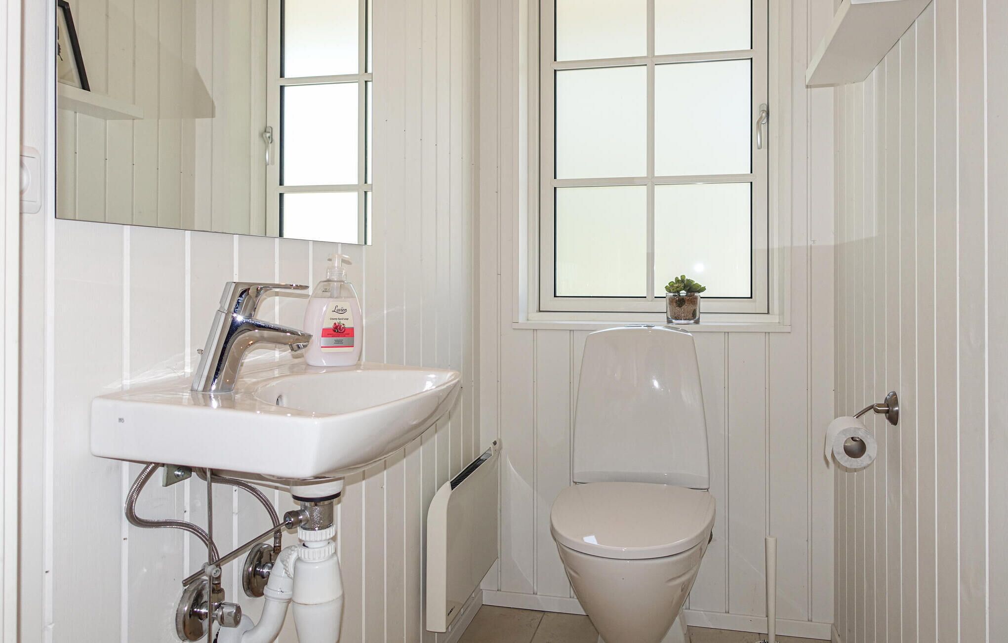 Ein Badezimmer mit einem weißen Waschbecken, einer Toilette und einem Fenster.