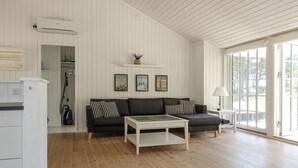A spacious living room with a dark grey sofa, a white coffee table, and a large window providing natural light. - 3 bedroom gorgeous home in Nexø (Nexø)