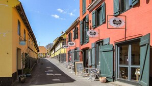 Une rue étroite bordée de bâtiments aux couleurs vives, dont certains arborent des enseignes indiquant la présence de restaurants.