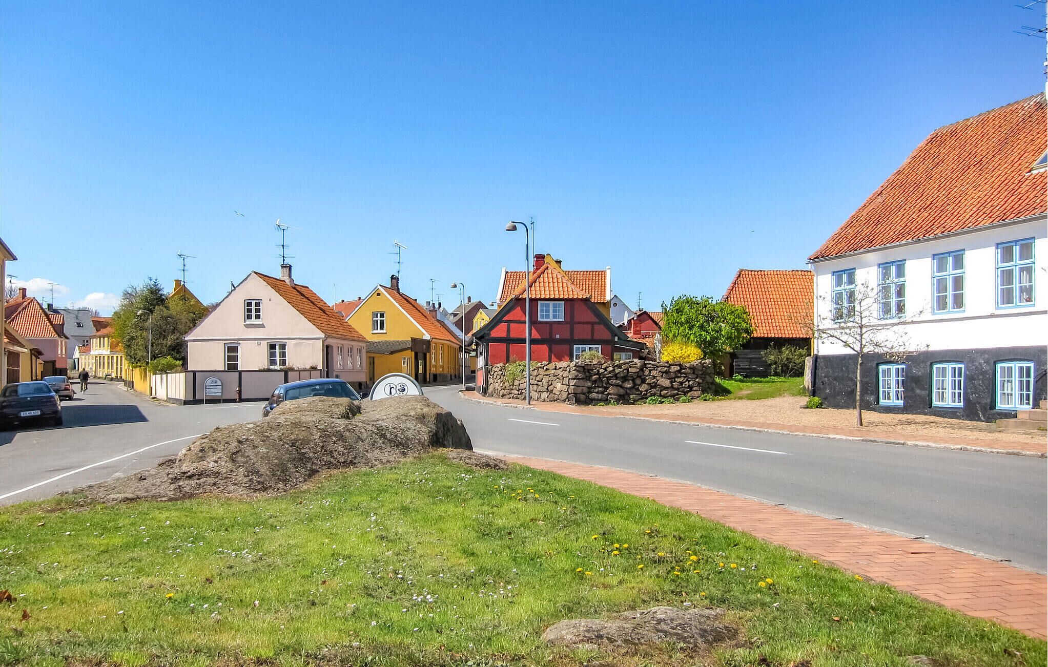 A street view with traditional houses, a clear sky, and a road with cars.