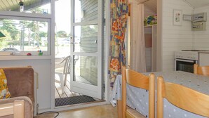 A small, cozy room with a wooden table, a chair, a window, and a door leading outside.