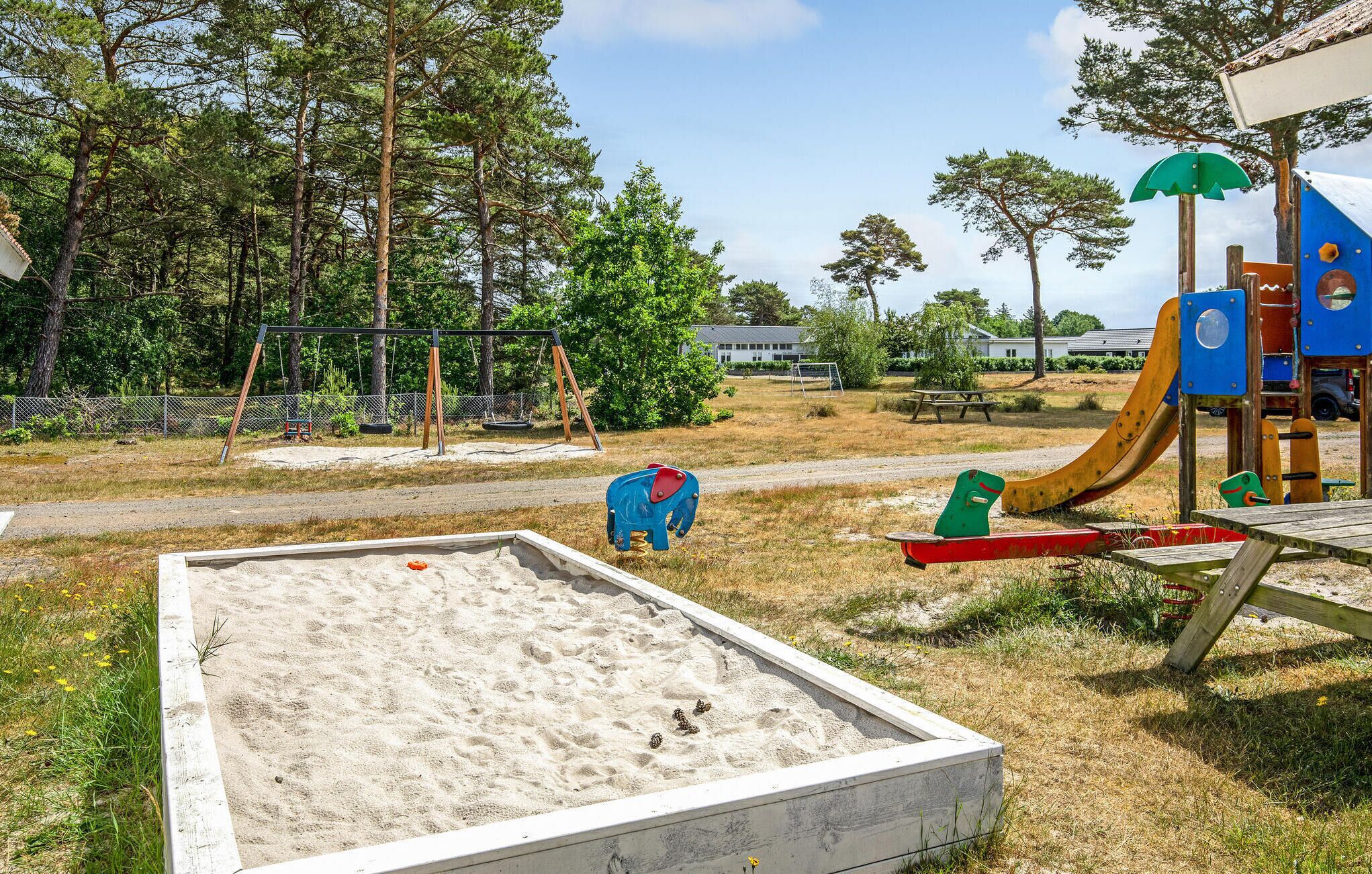 A playground with a sandpit, swings, and a slide.