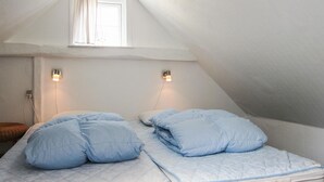 A small, cozy room with a sloped ceiling, a bed with blue bedding, and two wall-mounted light fixtures. - 2 bedroom nice apartment in Gudhjem (Gudhjem)