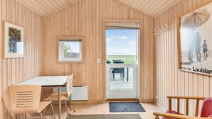 Een houten interieur met een eetgedeelte, een klein raam en een deur naar buiten.