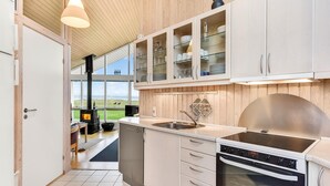 Een moderne keuken met witte kasten, een roestvrijstalen afzuigkap en een groot raam met uitzicht op een gazon.