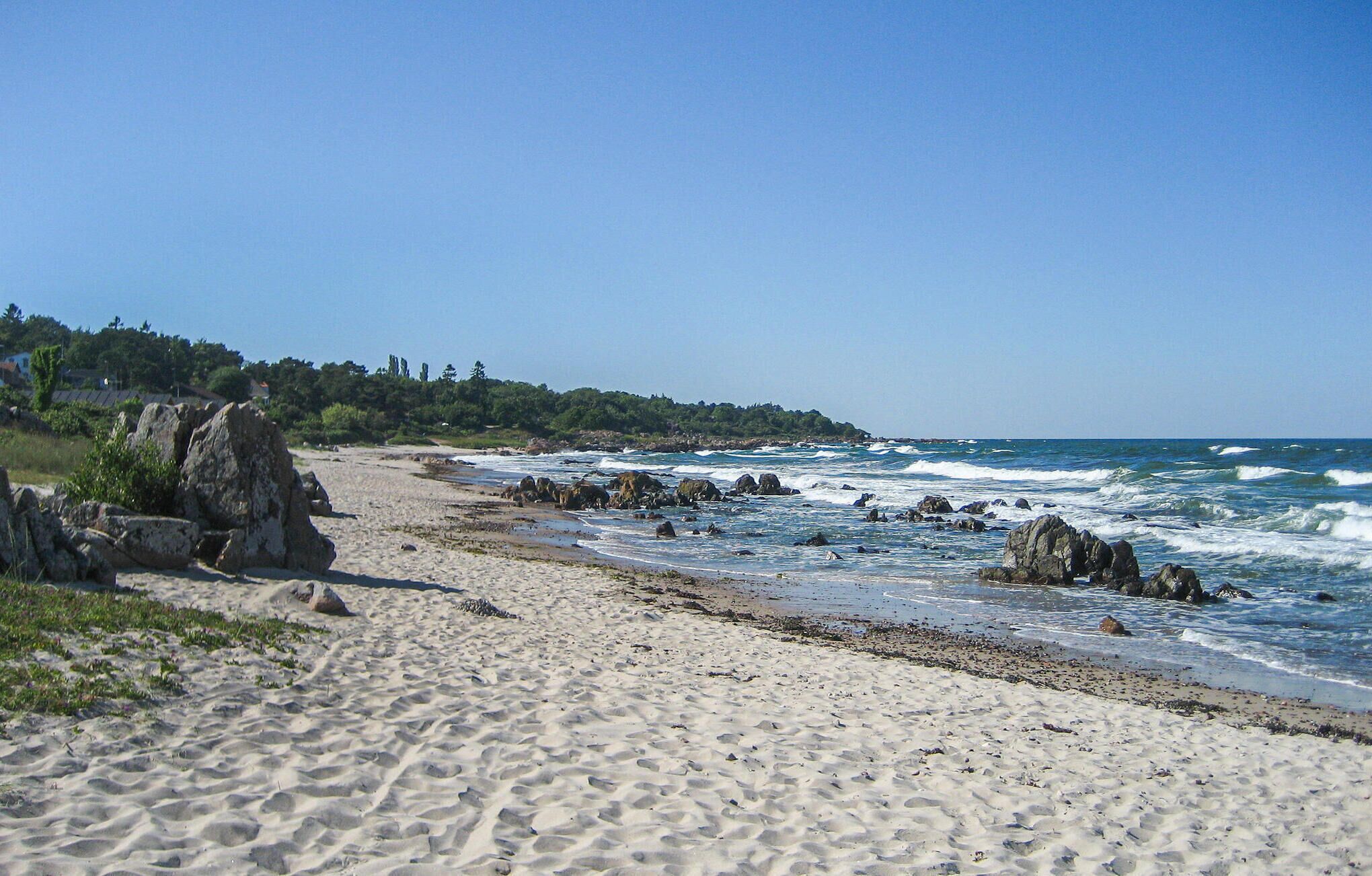 Une plage de sable avec de gros rochers et des vagues qui déferlent sur le rivage.