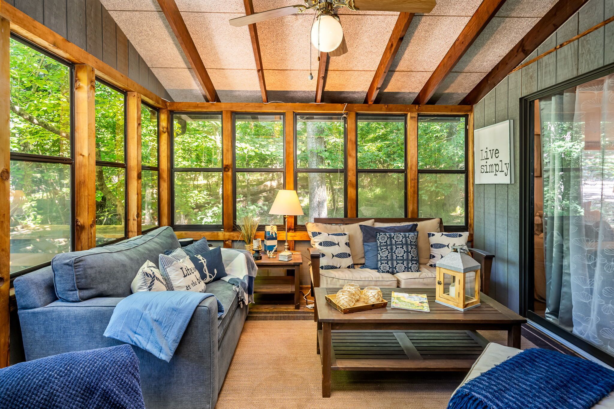 Een gezellig interieur van een chalet met een bank, een bijzettafeltje en een lamp.