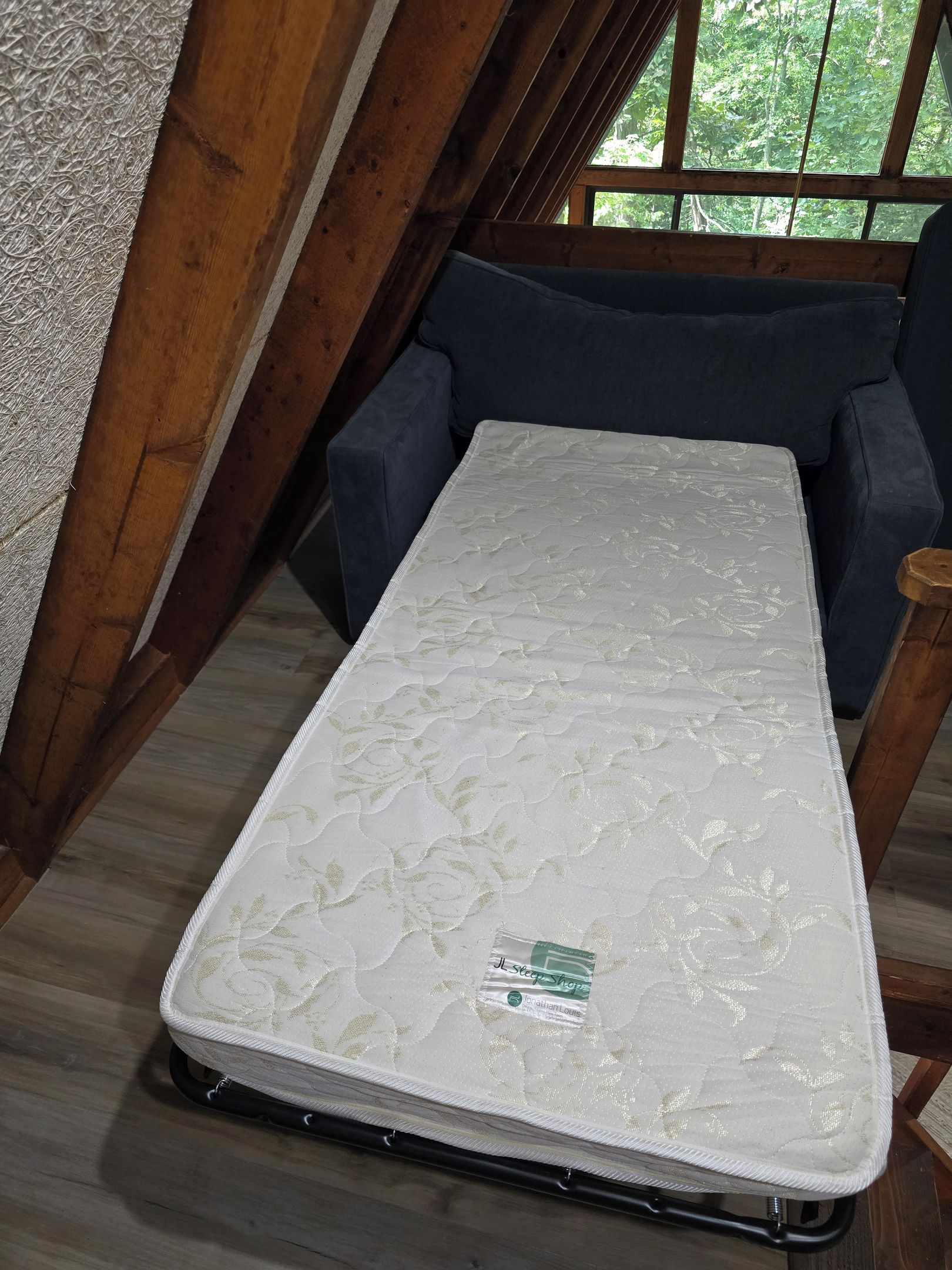 Eine Matratze in einem Zimmer mit Holzbalken und einem Fenster.