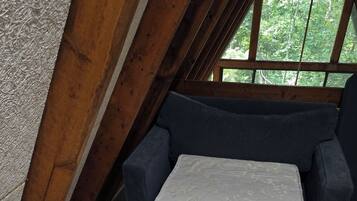 Eine Matratze in einem Zimmer mit Holzbalken und einem Fenster.